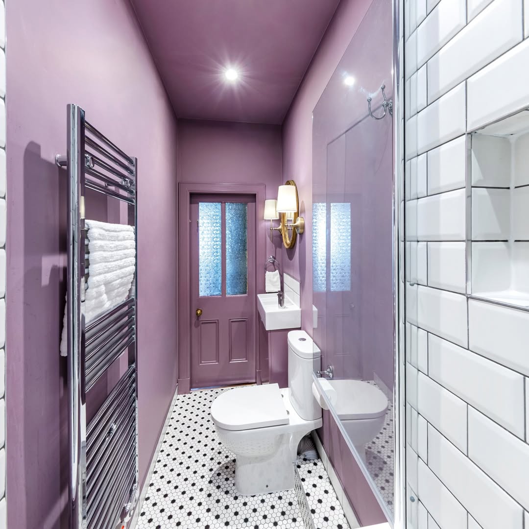 Compact Edinburgh tenement bathroom by Forazzi Bathrooms — Omnitub Deluxe 1700 × 750mm white deep soaking tub at the far end of a narrow bathroom with deep mauve walls, brass sconce and monochrome hexagonal floor tiles — handmade in Britain