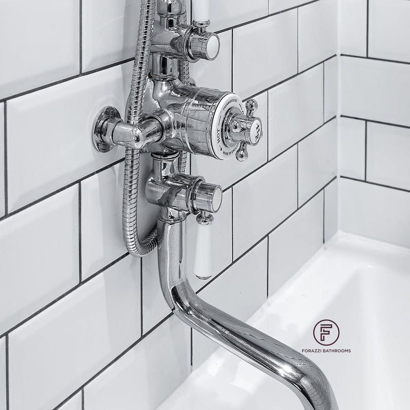 The full room from the tub end — mauve walls and ceiling, brass sconce, wall-mounted sink, and monochrome hex floor. A narrow space that doesn't feel like a compromise.