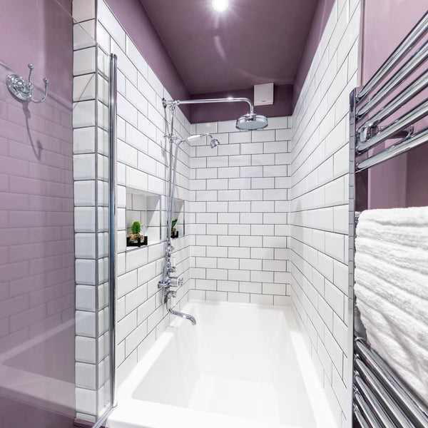 Top-down view of Omnitub Deluxe 1700 × 750mm white deep soaking tub with chrome thermostatic shower valve and white subway tile alcove — 600mm internal depth, handmade in Britain