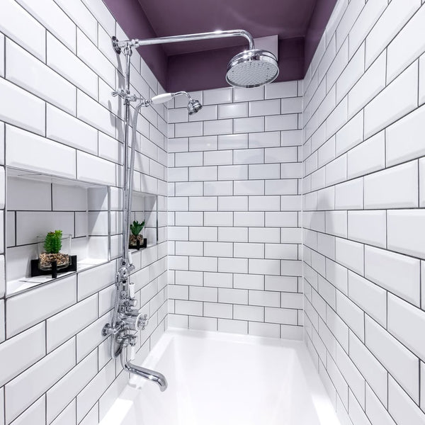 Traditional chrome thermostatic shower valve and bath filler close-up against white subway tile, sitting on the rim of an Omnitub Deluxe 1700 × 750mm white deep soaking tub by Forazzi Bathrooms