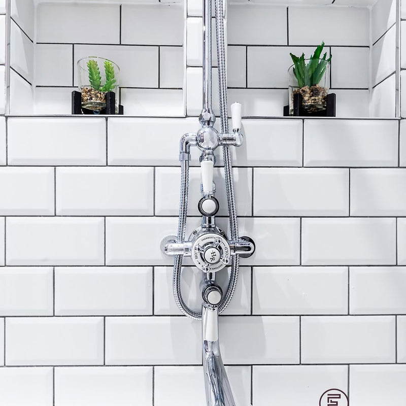 Recessed niches with succulents either side of a traditional thermostatic shower — practical storage built into the subway tile surround above the Omnitub.