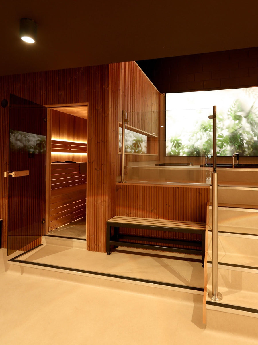 Matte-black seated tub beneath the backlit botanical wall