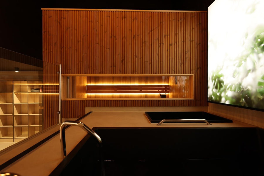 Backlit cedar niche above the black tub