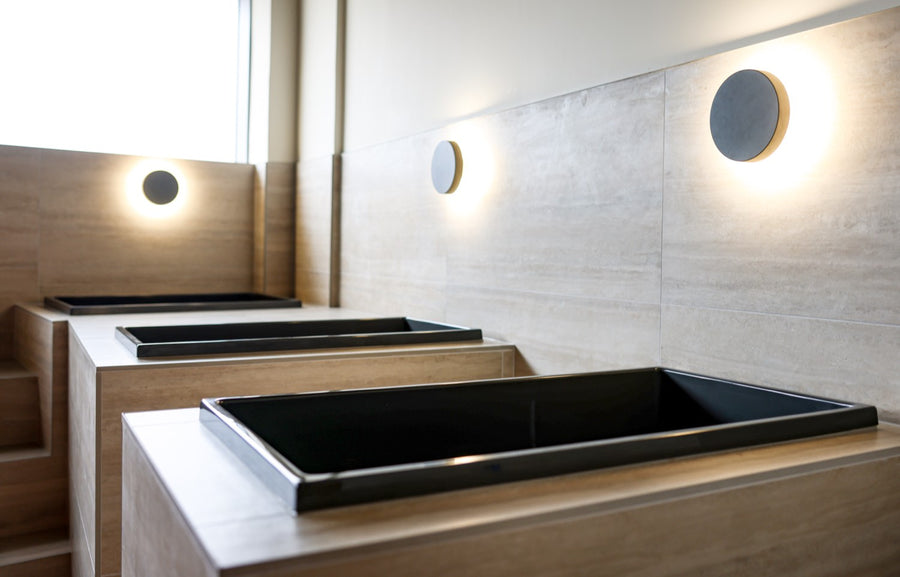 A run of black Omnitub plunge tubs under wall-lights