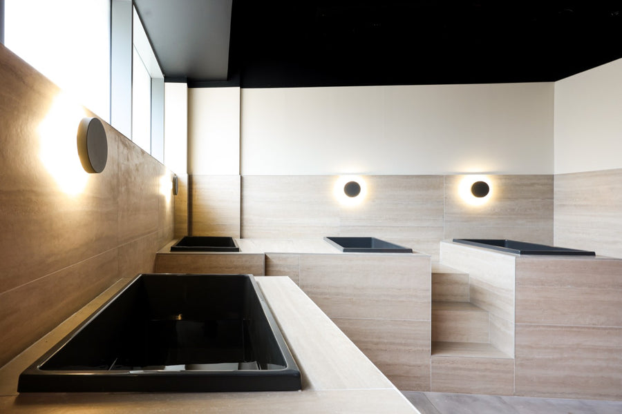 Single black tub with a honed travertine surround