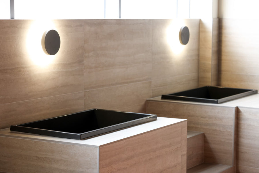 Deck-set black tubs under a soft wall-wash