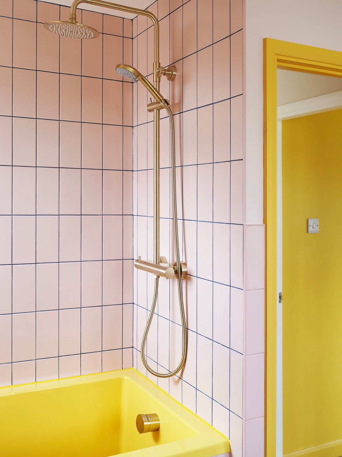 Bright yellow Omnitub bath and brushed brass shower in a colour-styled bathroom — one colour, head to toe