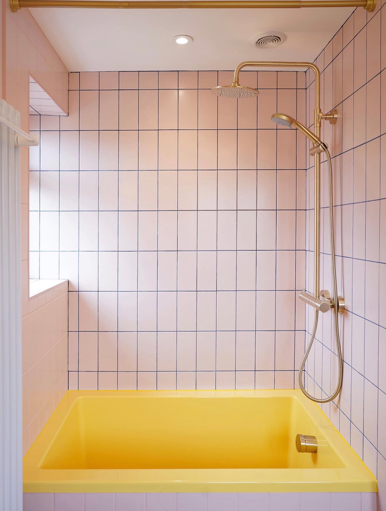 Bright yellow Omnitub deep soaking bath in a blush-pink tiled bathroom — handmade in Britain